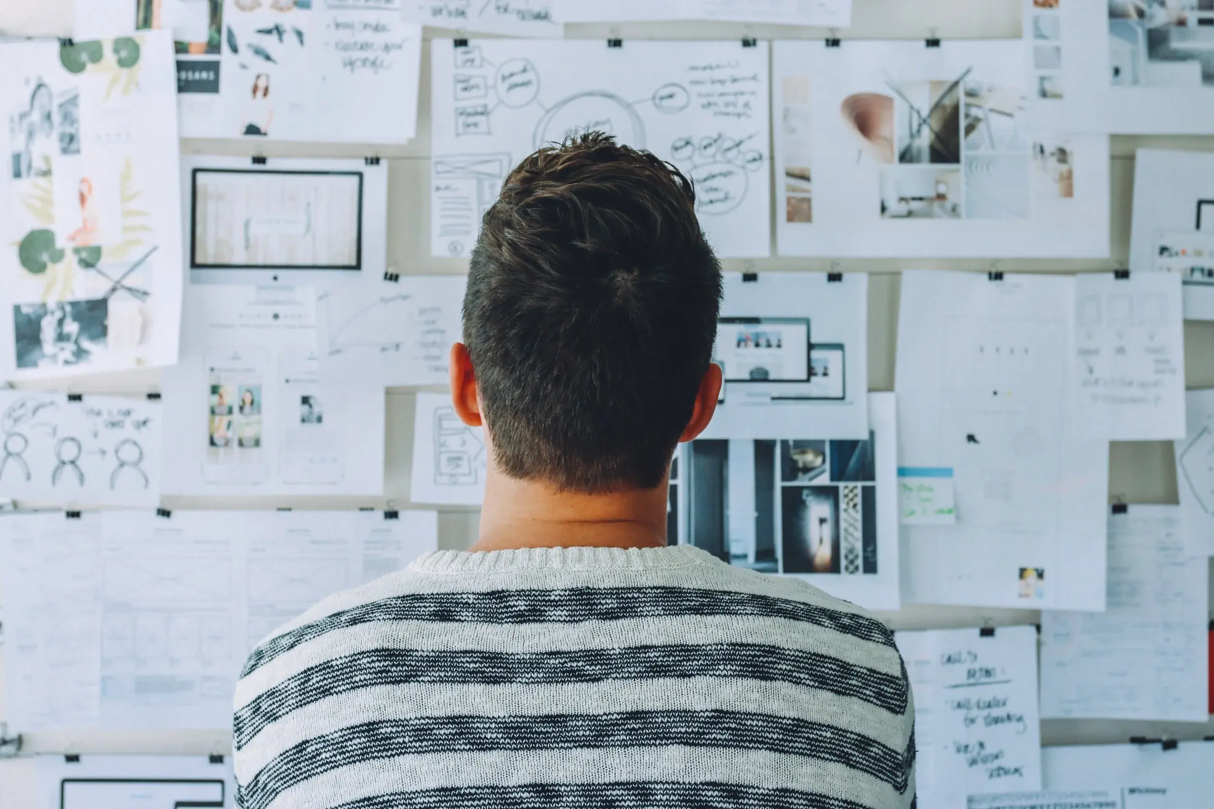 A person contemplating a complex brainstorming board filled with diagrams and ideas, symbolizing strategic planning and deep data analysis.
