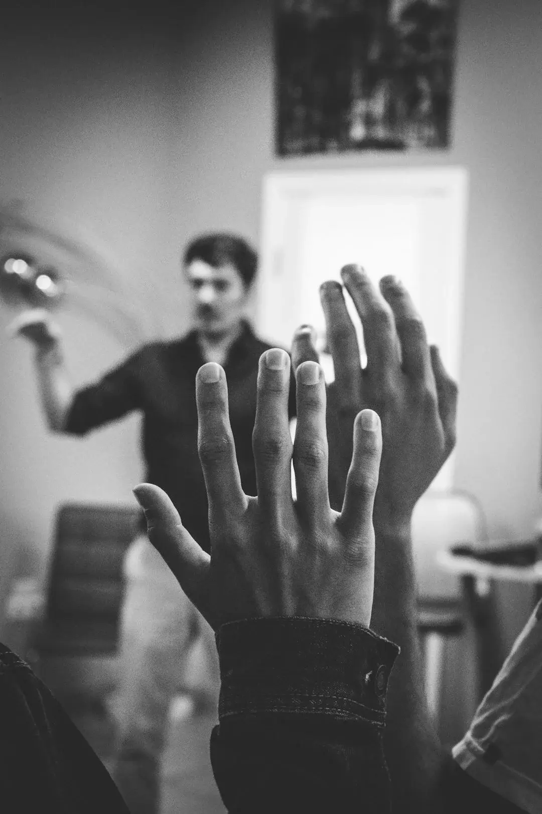 A group of hands raised in a discussion, representing active participation, questioning, and sparking new ideas or insights.