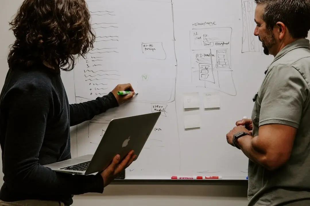 Professionals brainstorming around a whiteboard filled with diagrams, illustrating the acceleration and strategic development of data products.