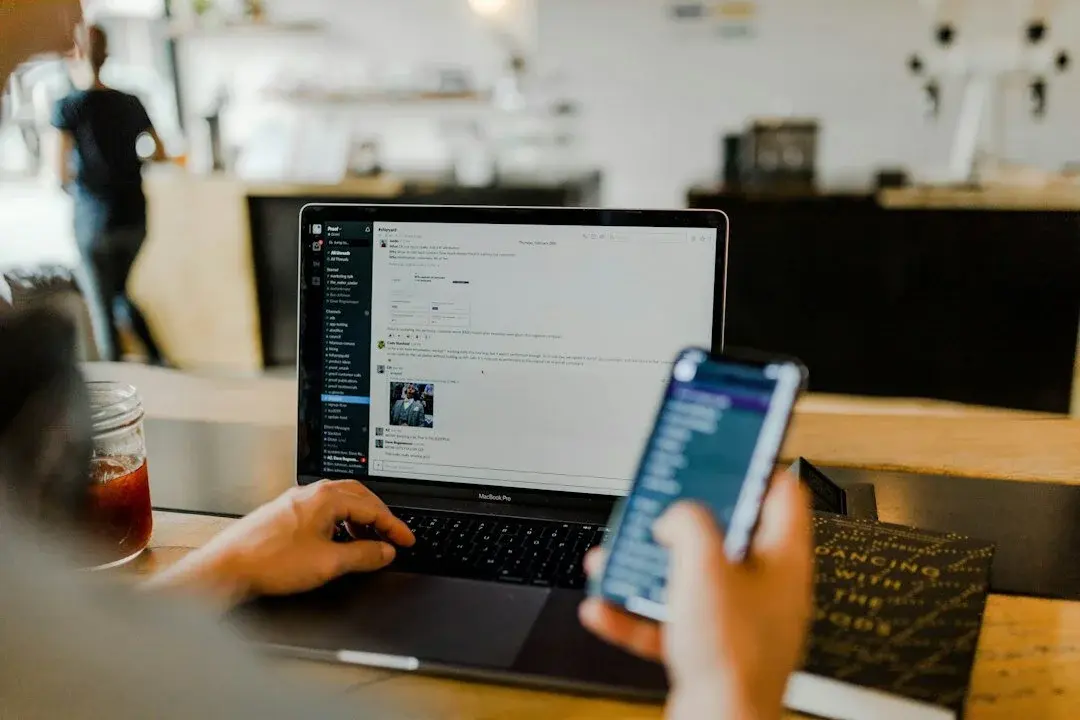 A person working at a table with laptops and notes, implementing the setting up of new systems.